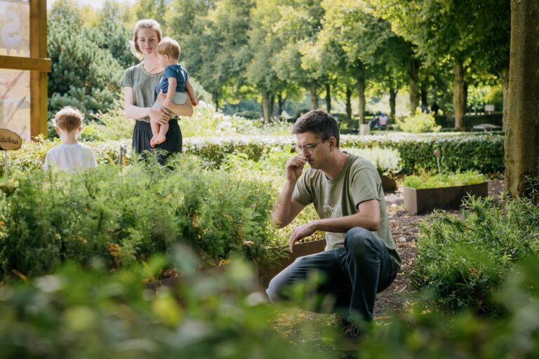 Ein Junger Mann riecht an Kräutern im Kräutergarten.