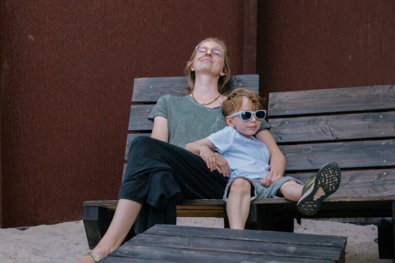 Eine Frau mit ihrem kleinen Sohn sitz auf einer Holzbank.